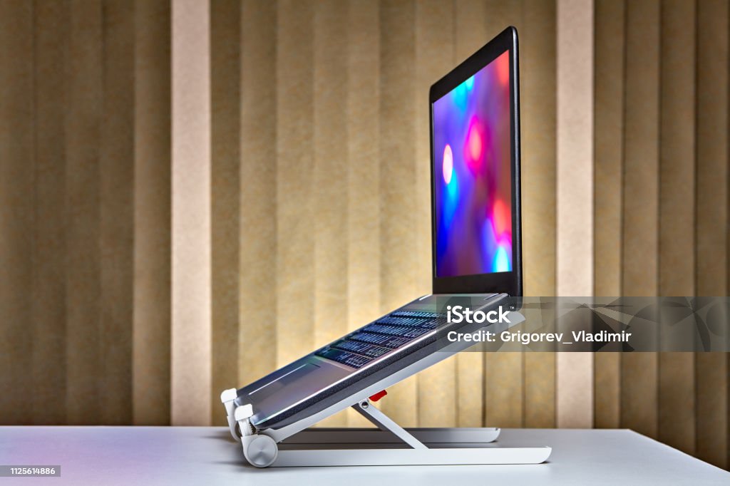 Dyazo silver adjustable aluminum portable laptop stand setup on a wooden office desk.